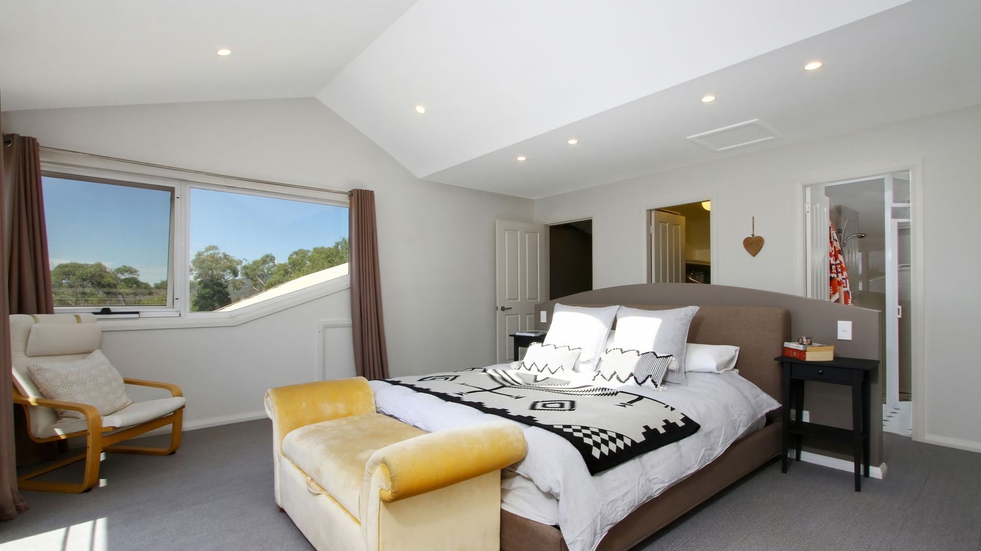 Une chambre avec un grand lit, une fenêtre, une chaise et un bureau.