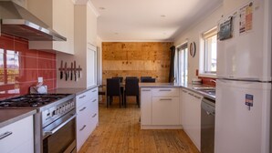 Een moderne keuken met een houten wand, witte kasten en een roestvrijstalen fornuis.