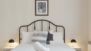 A bed with a metal frame, white bedding, and two bedside lamps. - Lake View 4, central location, comfortable and convenient (Jindabyne)