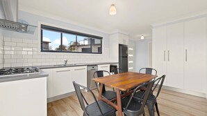 Una cocina moderna con armarios blancos, un refrigerador de acero inoxidable y una mesa de madera con cuatro sillas.