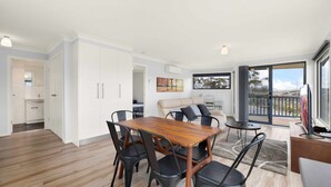 Un apartamento moderno con comedor, un conjunto de sofás y un balcón con vistas.