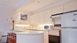 A modern kitchen with a central island, a built-in oven, and a microwave. - Karoonda 6 is warm and welcoming three bedroom apartment. (Thredbo)