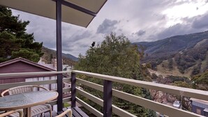 A balcony with a table and chairs, overlooking a mountainous landscape. - Karoonda 6 is warm and welcoming three bedroom apartment. (Thredbo)