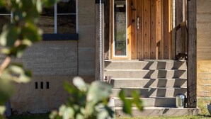 A building with a wooden door, a set of concrete steps leading up to the entrance, and a small window to the left. - Old Hut Creek Chalet with a peaceful rural outlook (Jindabyne)