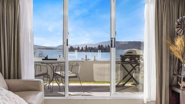 A balcony with a view of a lake, a grill, and a dining area with chairs and a table. - Horizons 307, resting on the shores of Lake Jindabyne (Jindabyne)