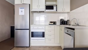 A modern kitchen with stainless steel appliances, white cabinetry, and a built-in microwave. - Horizons 307, resting on the shores of Lake Jindabyne (Jindabyne)