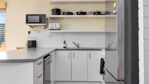 Eine moderne Küche mit weißen Schränken, einer Mikrowelle, einem Toaster und einem Spülbecken.