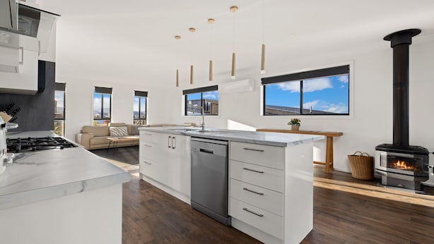A modern kitchen with a central island, built-in dishwasher, and a wood-burning stove.