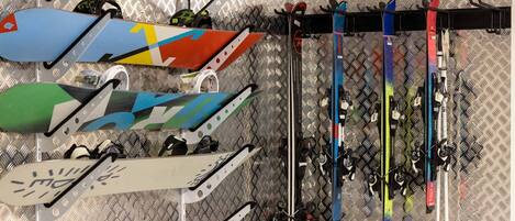 A variety of skis and snowboards arranged on a metal surface.