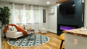 Una sala de estar con sofá, alfombra redonda, televisor y chimenea.