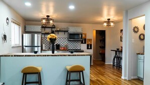 Una cocina moderna con una isla central, taburetes de bar e iluminación colgante.