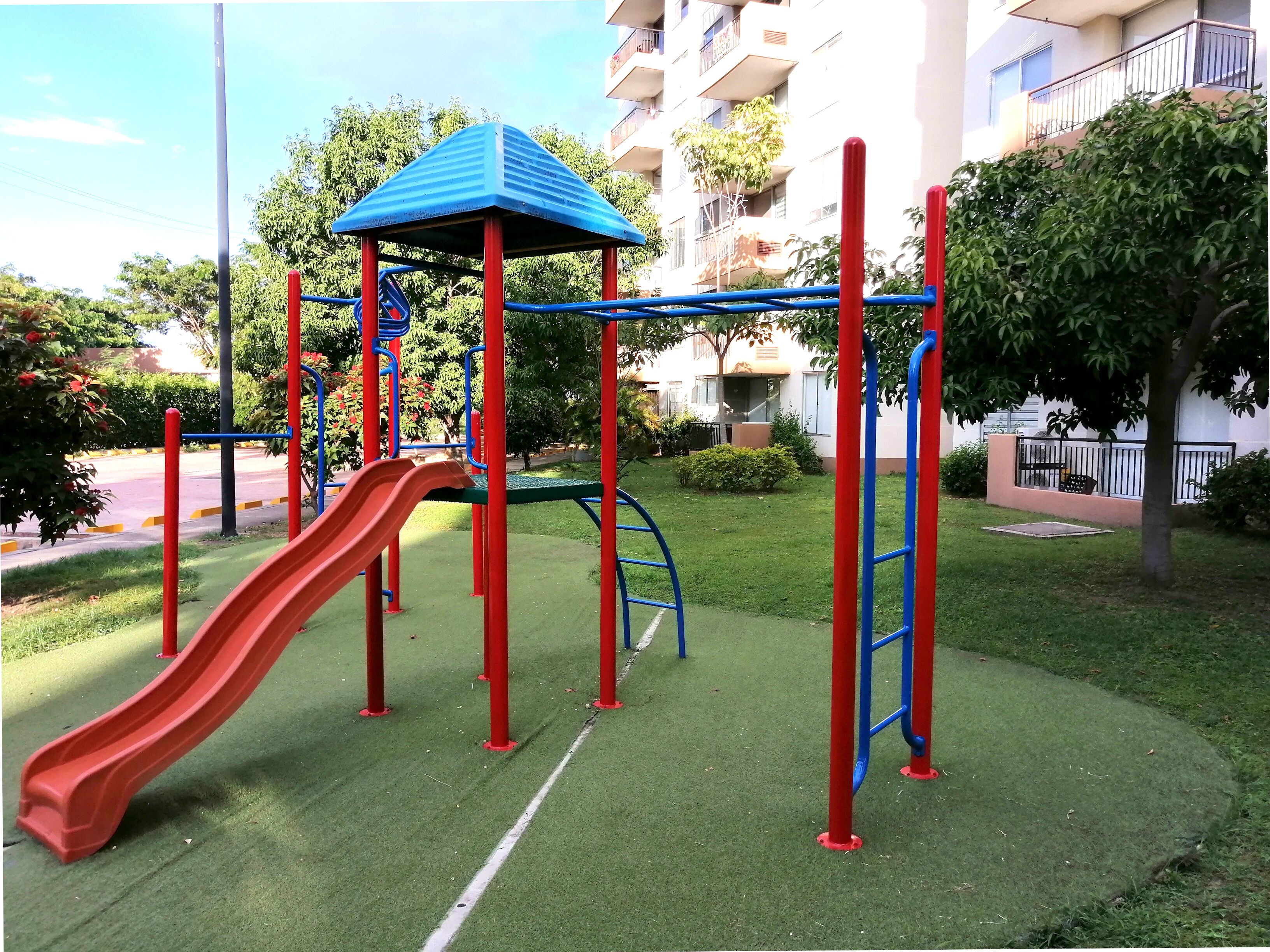 A playground with a red slide and a blue climbing structure.