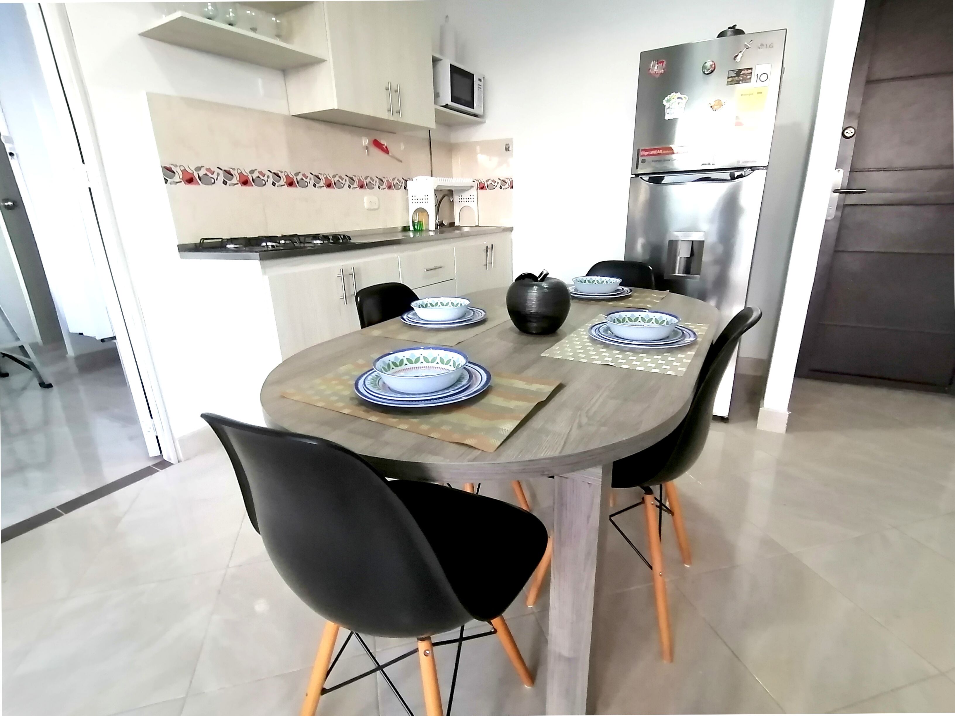 A modern kitchen with a dining table set for six, equipped with black chairs and a central vase.
