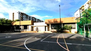 An outdoor basketball court with clear markings, surrounded by buildings with balconies and large windows. - Confortable Apartamento Vacacional  (Ricaurte)
