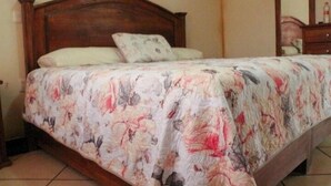 Et soveværelse med sengegavl i træ, blomstret sengetøj og et natbord.