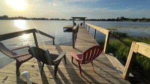 A wooden pier extending over calm water with chairs and a gazebo. - Come and enjoy a family stay in a beatiful Lake House. (Lake Placid)