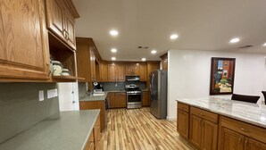 A modern kitchen with wooden cabinets, stainless steel appliances, and a marble countertop. - Come and enjoy a family stay in a beatiful Lake House. (Lake Placid)