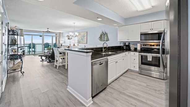 A modern kitchen with stainless steel appliances, a central island, and a view to the outside. - Laguna Keyes 709 - Oceanfront 3BD/3BA (North Myrtle Beach)