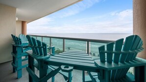 A balcony with teal Adirondack chairs and a table, overlooking a calm sea and clear sky. - Laguna Keyes 709 - Oceanfront 3BD/3BA (North Myrtle Beach)