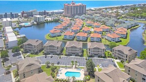 A residential area with a large body of water, a central swimming pool, and a high-rise building in the background.