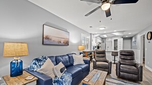A modern living room with a blue sofa, two leather recliners, a wooden coffee table, and a ceiling fan.