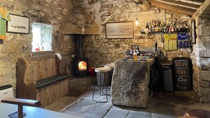Un intérieur rustique avec un mur en pierre, un banc en bois et une cheminée.