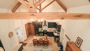 Une cuisine moderne avec des meubles de couleur sombre, un coin repas doté d’un canapé bleu clair et une structure de plafond en bois.