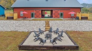 Une grange rouge avec une terrasse en gravier et un espace de détente extérieur.