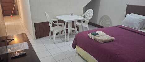 A hotel room with a bed, a desk, and a small table with chairs.