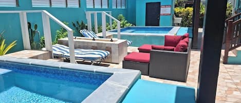 A pool area with lounge chairs and a small building labeled "POOL RULES".