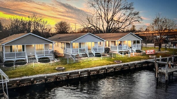 Three waterfront cabins with porches, a dock, and a 'For Rent' sign. - Wolf River Cabin B - Fremont, WI (Fremont)