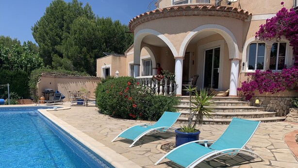 A swimming pool with lounge chairs, a stone patio, and a building with arches and a balcony. - Villa Lorena Avec Grande Piscine Privée, au Calme et a 3 km de la mer (L'Ametlla de Mar)