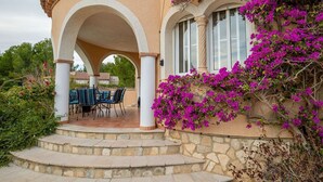 A covered outdoor seating area with stone steps leading up to a table and chairs. - Villa Lorena Avec Grande Piscine Privée, au Calme et a 3 km de la mer (L'Ametlla de Mar)