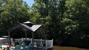 A wooden deck with a covered seating area, a small fire pit, and a pond. - Relax with Nature (Coldwater)