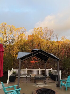 A covered outdoor seating area with a pergola, white railing, and a fire pit. - Relax with Nature (Coldwater)