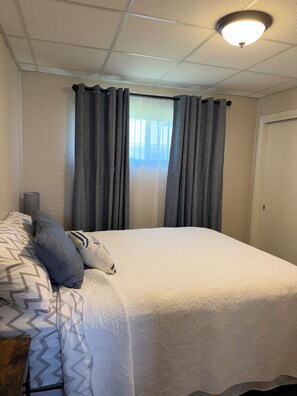 A bedroom with a bed, curtains, a window, and a ceiling light. - Relax with Nature (Coldwater)