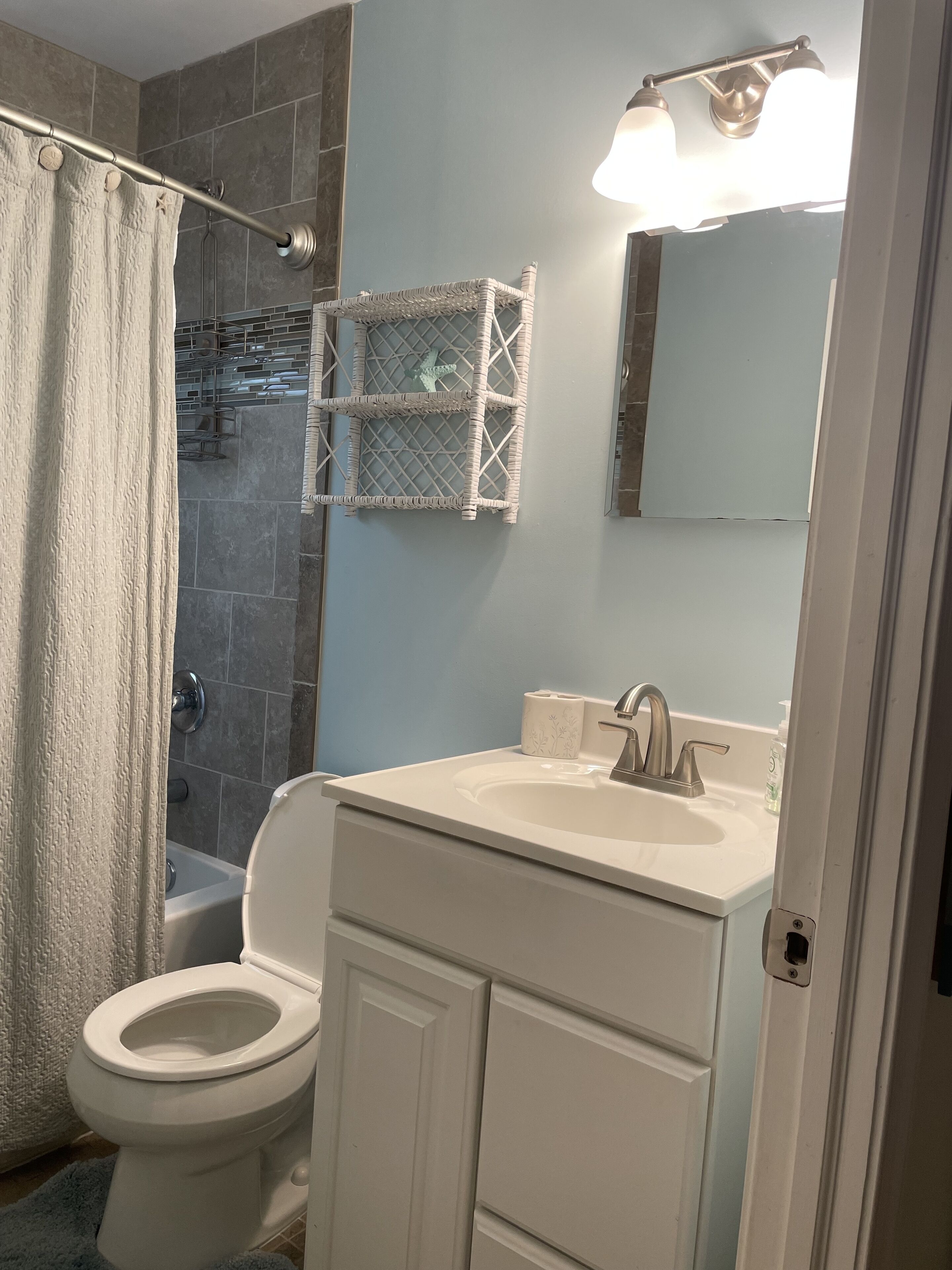 A bathroom with a white toilet, a sink with a mirror, and a shower area with a curtain.
