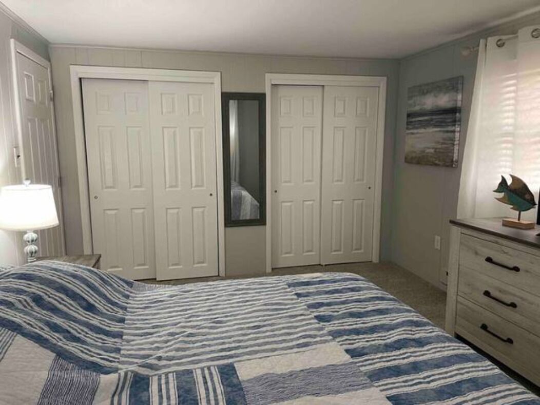 A bedroom with a bed, a dresser, and two doors.