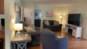 Een woonkamer met een bank, fauteuil en tv-meubel.