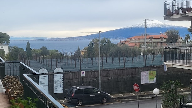 A view of a coastal area with a road, a stop sign, and a signpost with directions. - The White Lodge (Sorrento)