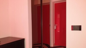 A hallway with a black and white striped floor, red doors, and a white wall with a small plaque. - The White Lodge (Sorrento)