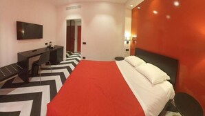 A modern hotel room with a large bed, a desk, a flat-screen TV, and a red accent wall. - The White Lodge (Sorrento)