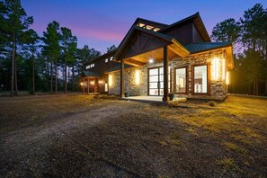 A modern log cabin with a stone exterior, large windows, and a covered porch. - Multi purpose building for weddings, family reunions, company parties, etc!!   (Broken Bow)