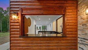 L’intérieur d’une cabane en rondins, avec un espace salon central, des murs en bois et un mur d’accent en pierre.