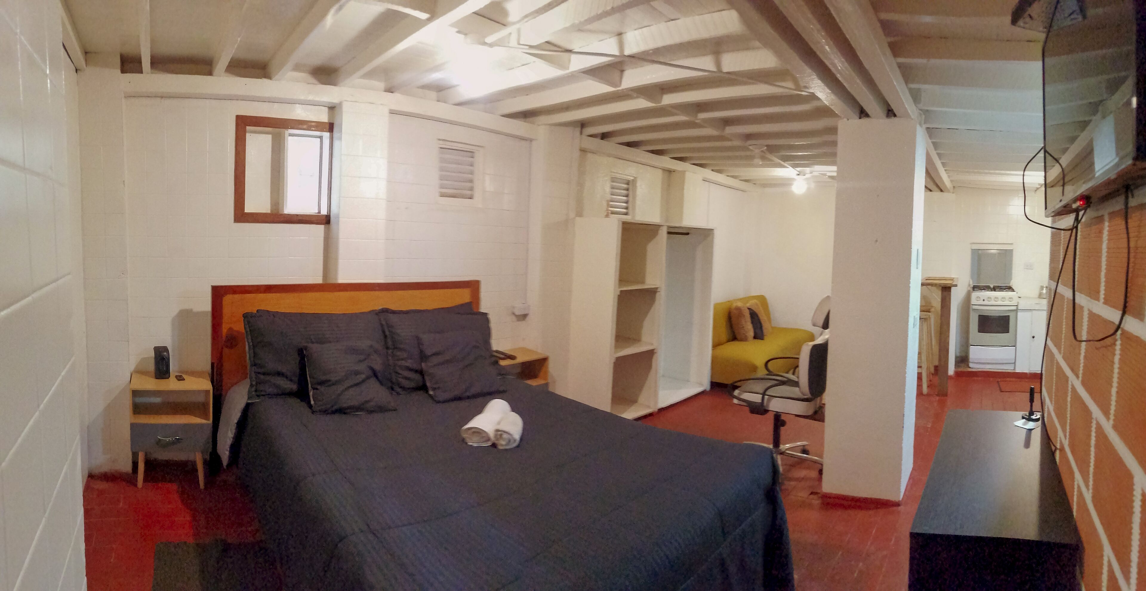 A bedroom with a bed, a nightstand, a chair, and a desk.