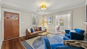 A living room with a brown leather sofa, blue armchairs, a wooden coffee table, and a patterned rug. - Charming Historic Marietta Home! (Marietta)