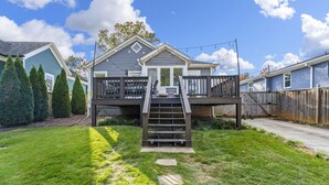 A residential property with a two-story deck, a staircase leading to the deck, and a well-maintained lawn. - Charming Historic Marietta Home! (Marietta)