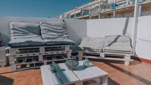 Una terraza en la azotea con dos sillones de relax, una mesita y faroles decorativos.