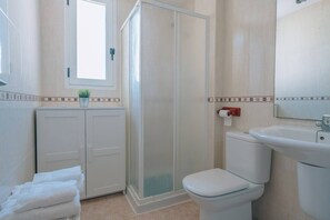 A bathroom with a toilet, sink, shower, and a cabinet with towels. - Vivienda Turística SunbeachXilxes CV-VUT0042192-CS (Xilxes)