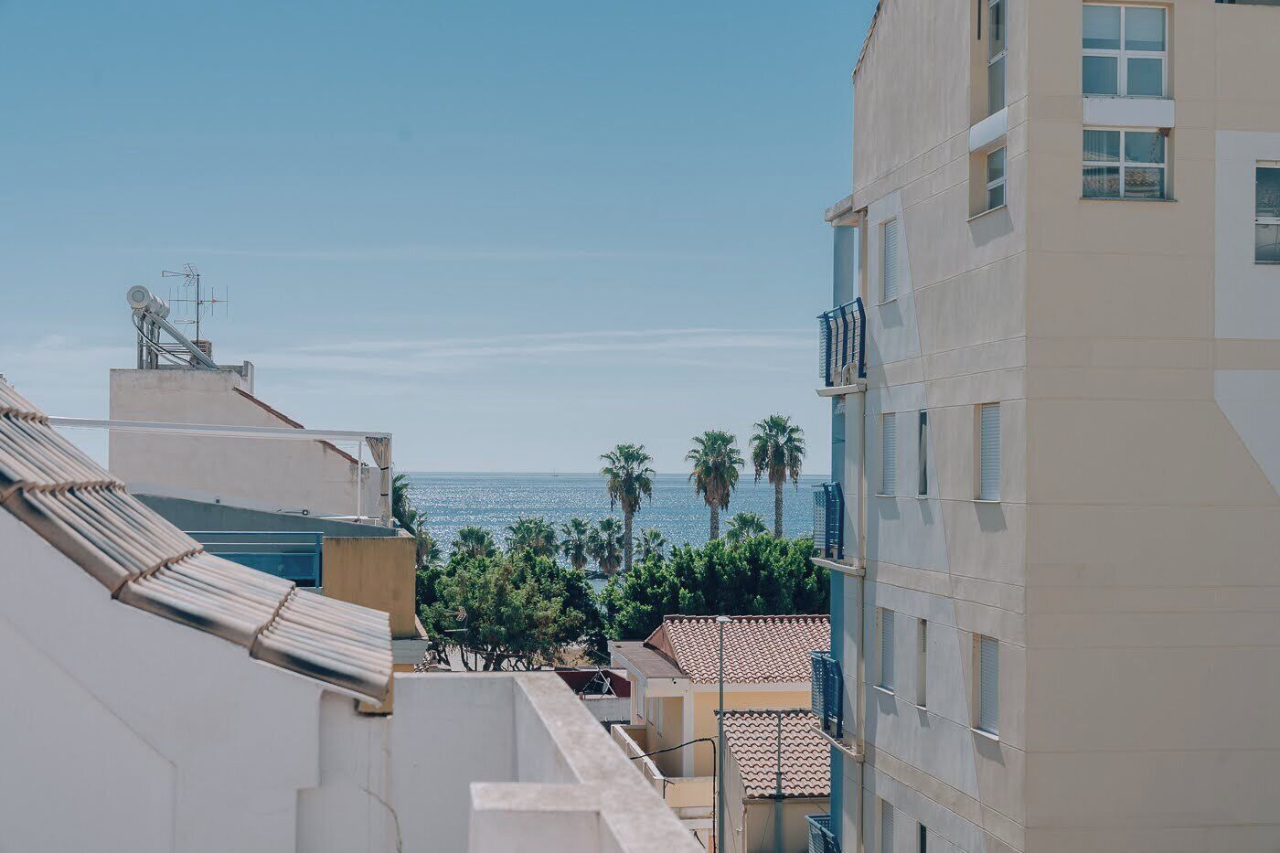 A view of a coastal area with buildings, a clear sky, and the sea in the distance.